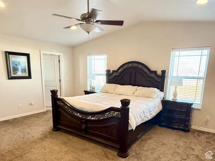 Carpeted bedroom featuring vaulted ceiling, multiple windows, a ceiling fan, and baseboards