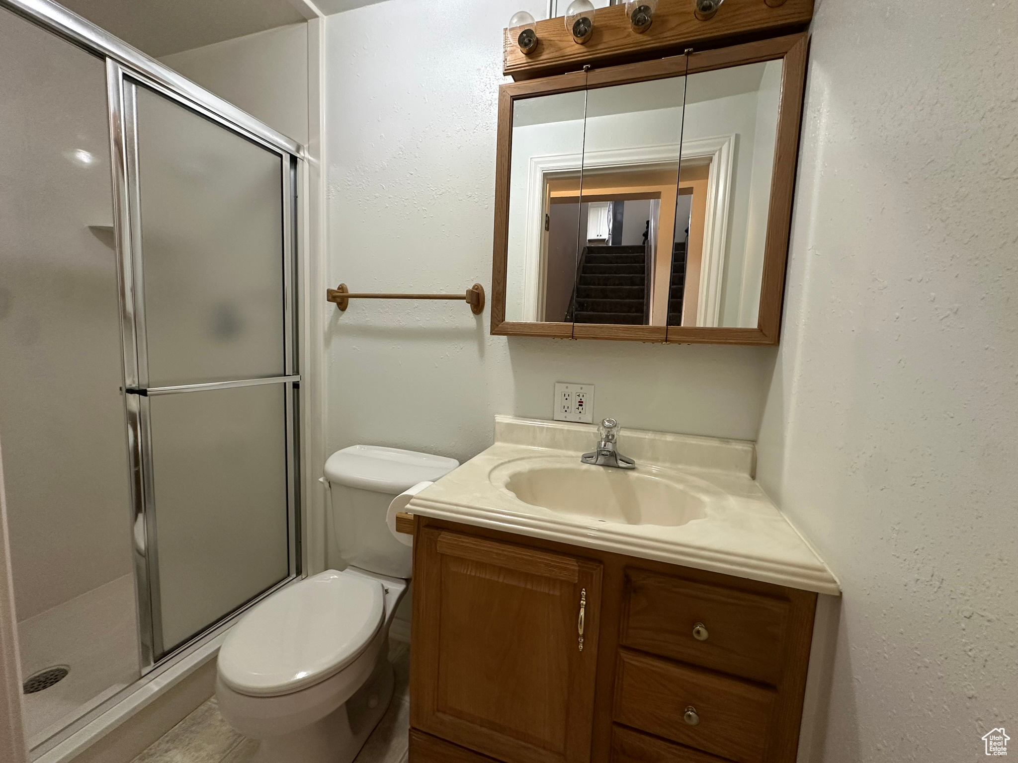 Full bathroom with toilet, a stall shower, and vanity