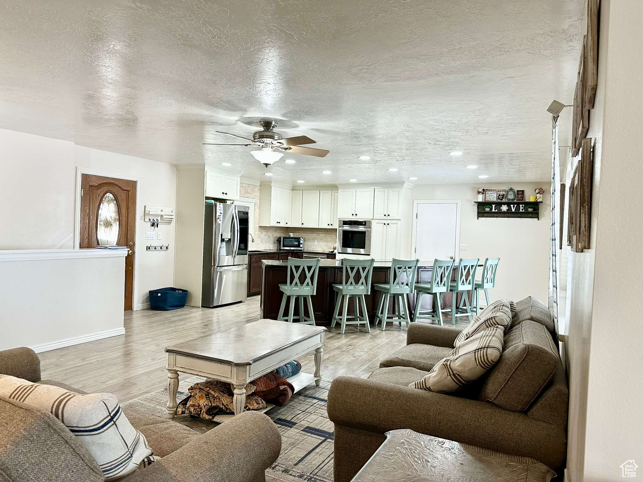 Living room with recessed lighting, a ceiling fan, a textured ceiling, light wood-type flooring, and baseboards