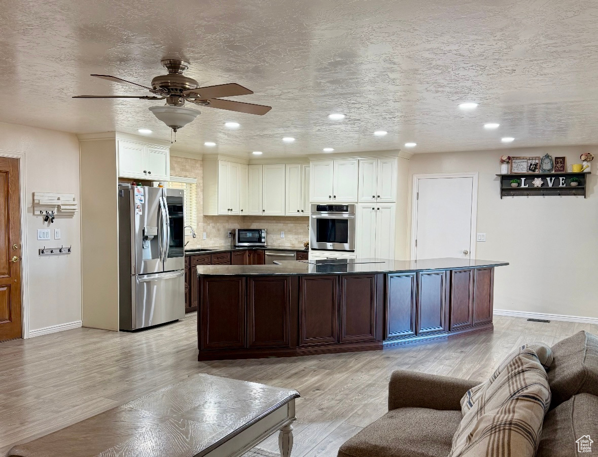 Kitchen with appliances with stainless steel finishes, white cabinetry, a sink, and light wood-style flooring