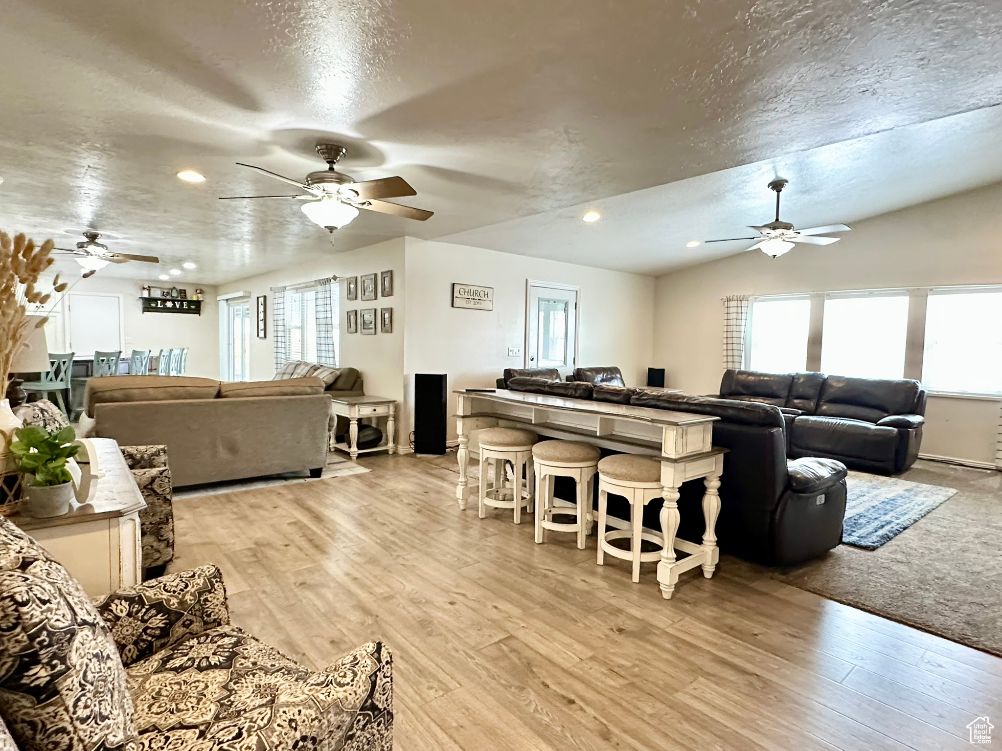 Living room featuring recessed lighting, light wood-style flooring, a ceiling fan, vaulted ceiling, and a textured ceiling