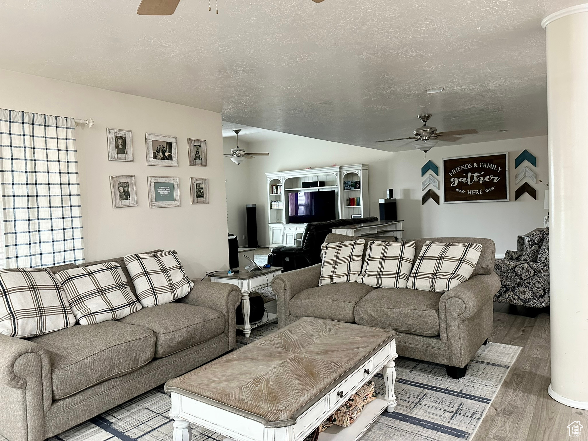 Living area featuring a textured ceiling, light wood finished floors, lofted ceiling, and a ceiling fan