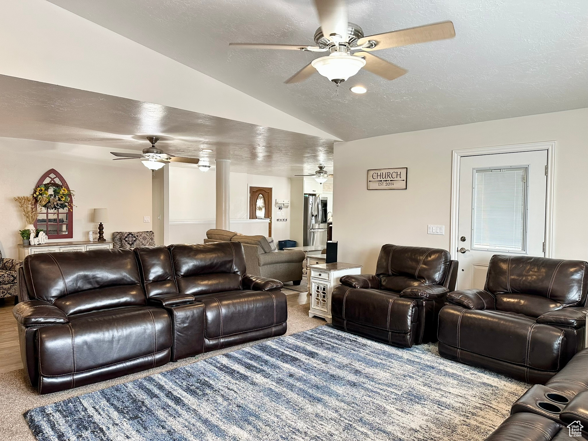 Living area with vaulted ceiling, a textured ceiling, and light colored carpet