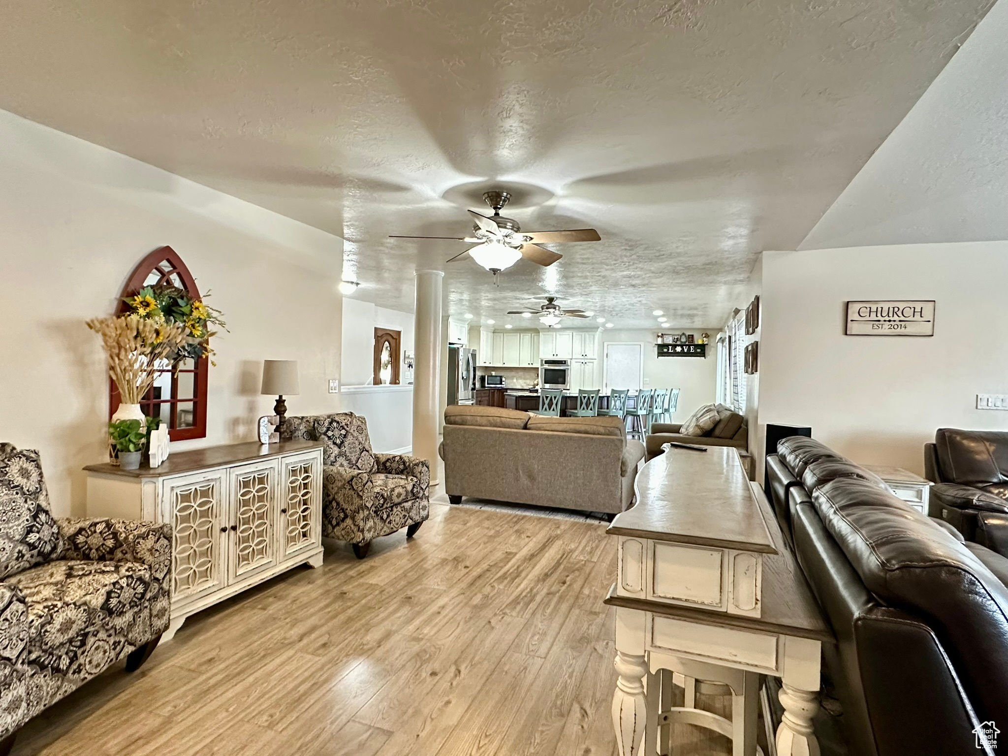 Living area with light wood-style floors, a ceiling fan, and a textured ceiling