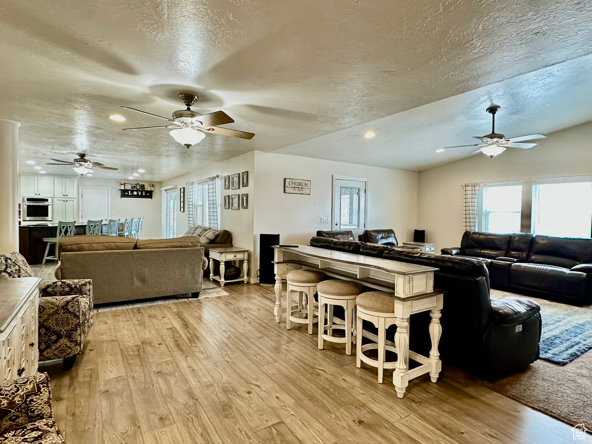 Living room featuring a textured ceiling, vaulted ceiling, light wood-style flooring, and recessed lighting