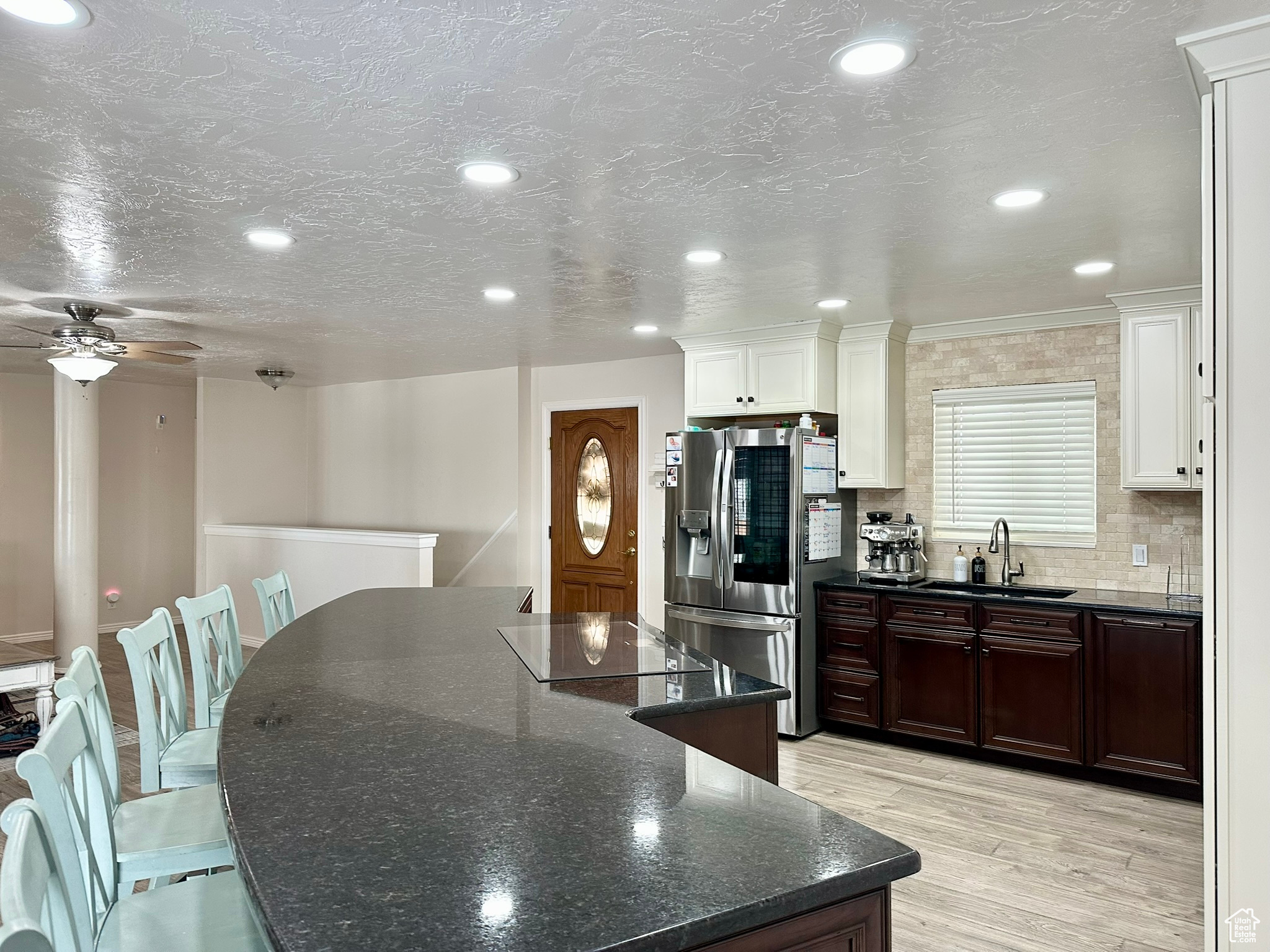 Kitchen featuring a sink, stainless steel fridge with ice dispenser, light wood-type flooring, backsplash, and a center island