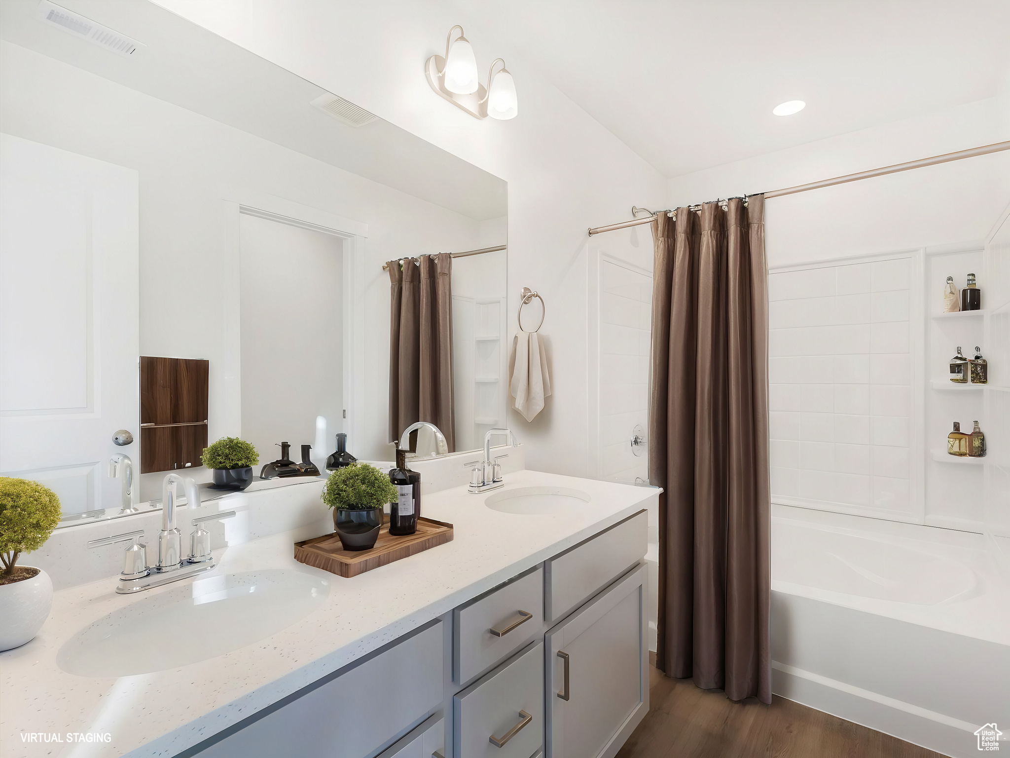 Full bathroom with double vanity, shower / tub combo, a sink, and visible vents