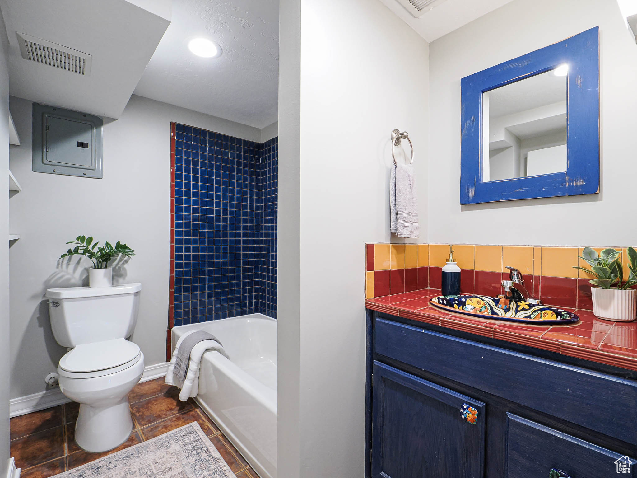 Full bath with toilet, vanity, baseboards, visible vents, and electric panel