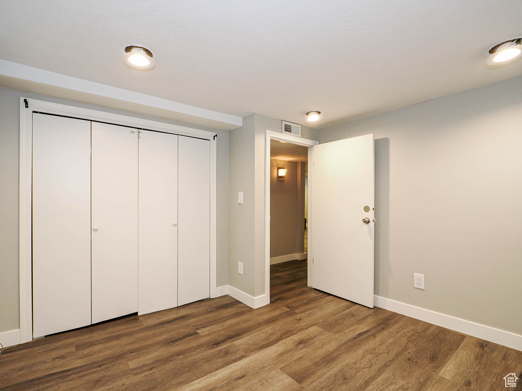 Unfurnished bedroom featuring baseboards, a closet, visible vents, and wood finished floors