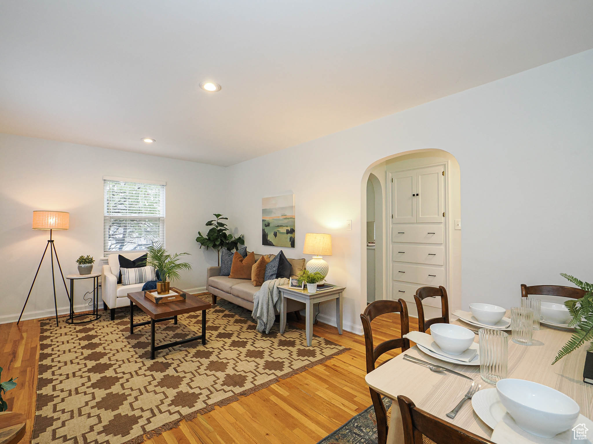 Living area featuring arched walkways, light wood-style flooring, baseboards, and recessed lighting