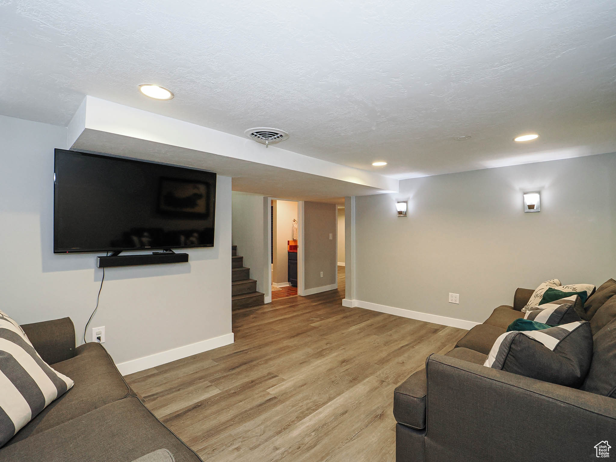 Living area featuring visible vents, a textured ceiling, light wood-style flooring, and baseboards