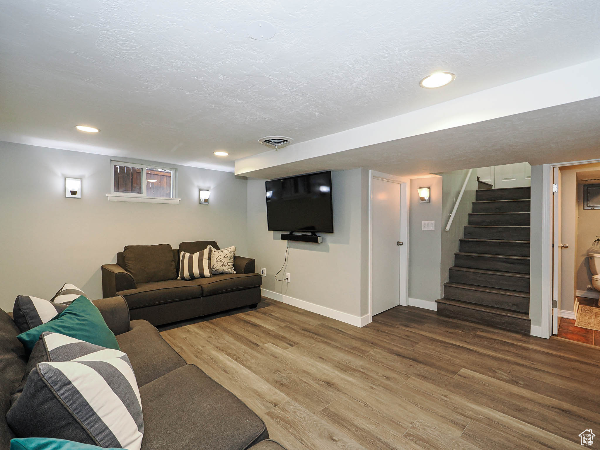 Living area with a textured ceiling, wood finished floors, and baseboards