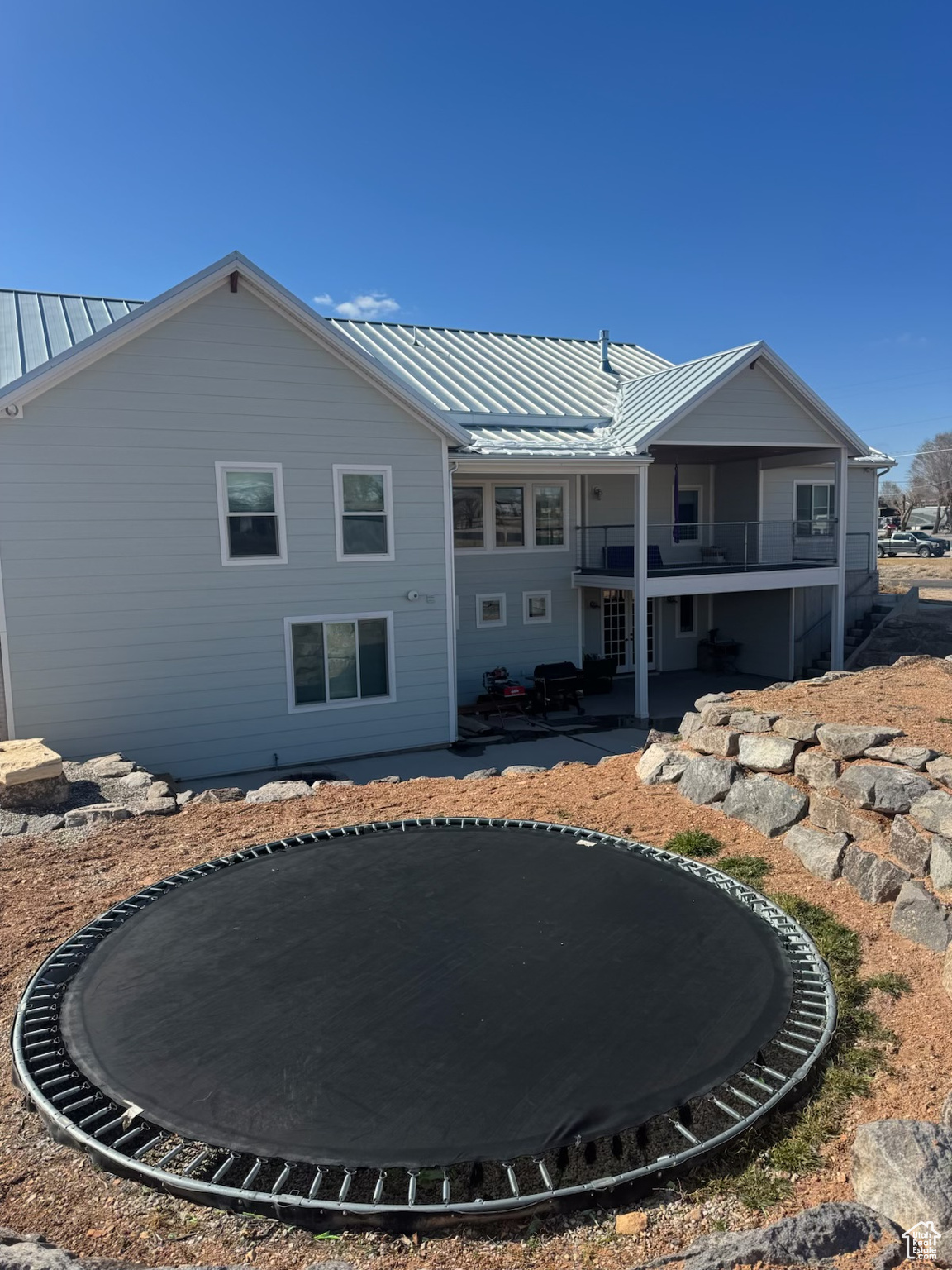 Rear view of house with a trampoline, a standing seam roof, a patio area, and metal roof