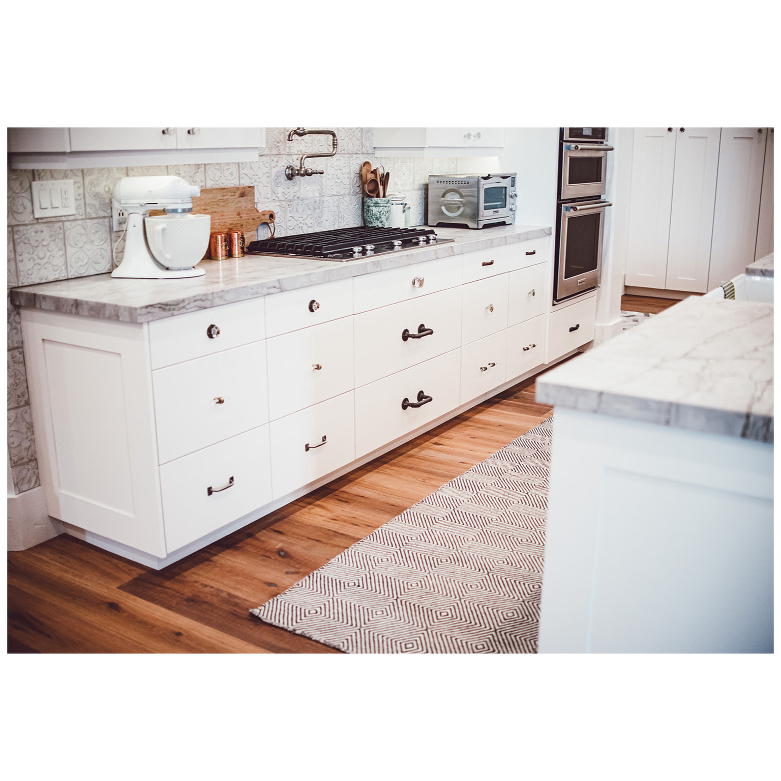 Kitchen featuring a toaster, appliances with stainless steel finishes, decorative backsplash, and light wood-style flooring