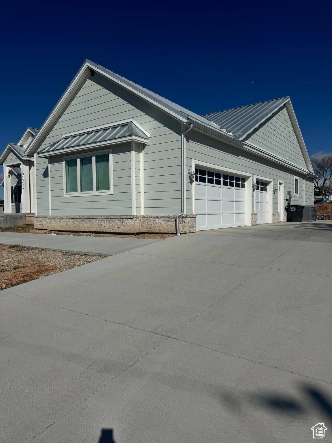 View of home's exterior featuring driveway, a standing seam roof, a garage, and metal roof