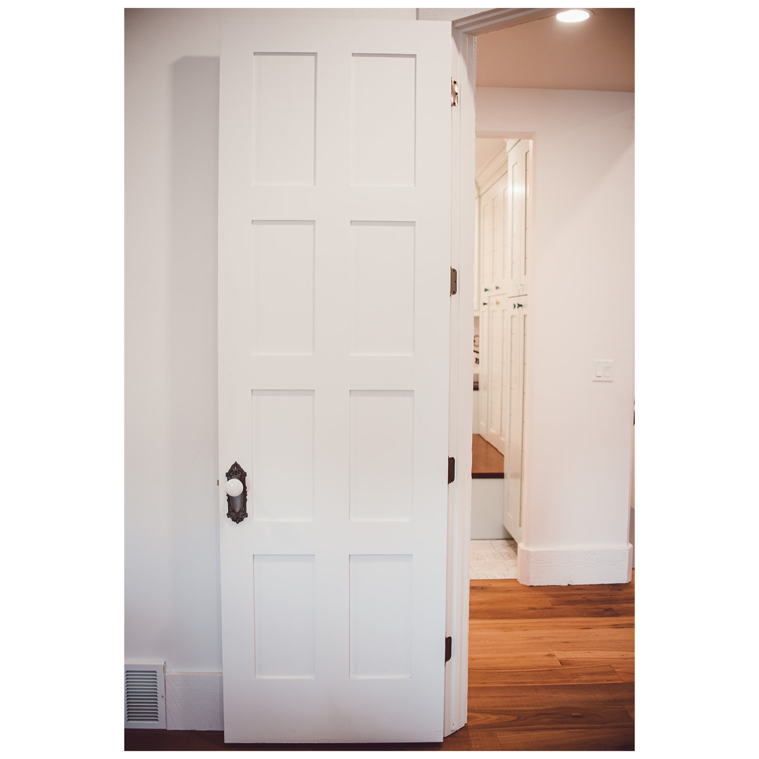 Hallway with light wood-type flooring, visible vents, and baseboards