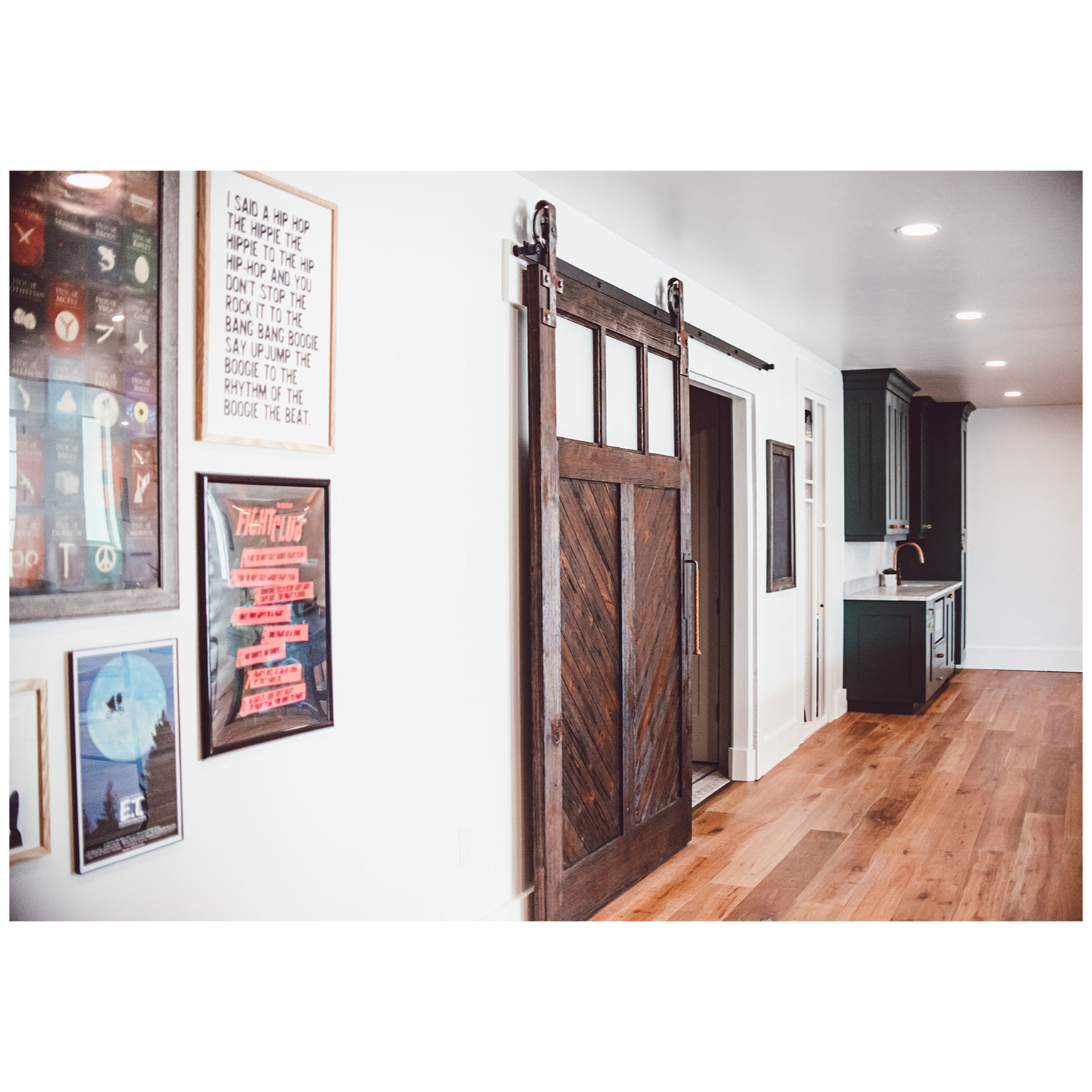 Hallway with a barn door, baseboards, light wood-type flooring, a sink, and recessed lighting