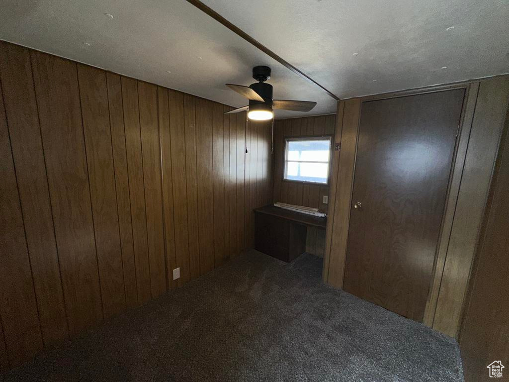 Interior space featuring carpet flooring, wood walls, and ceiling fan