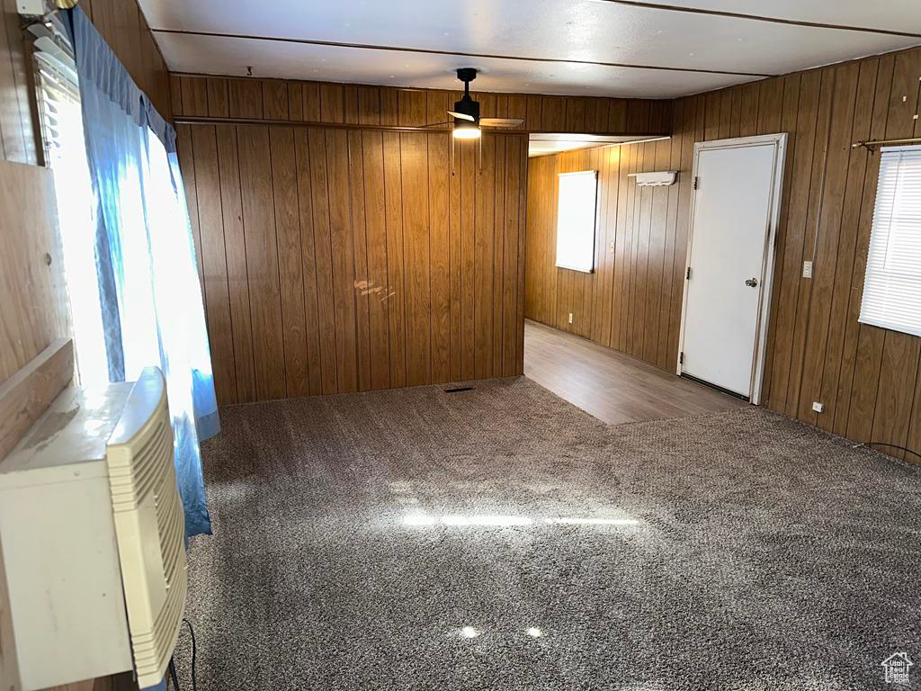 Carpeted empty room with wood walls and a ceiling fan