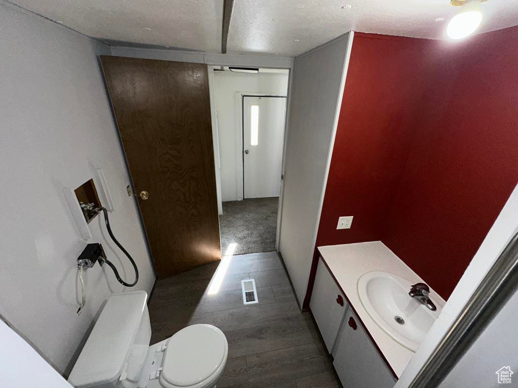 Bathroom with visible vents, toilet, wood finished floors, a textured ceiling, and vanity