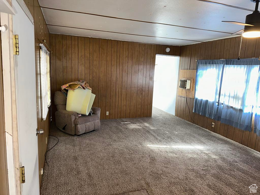 Unfurnished room featuring ceiling fan, carpet flooring, and wooden walls