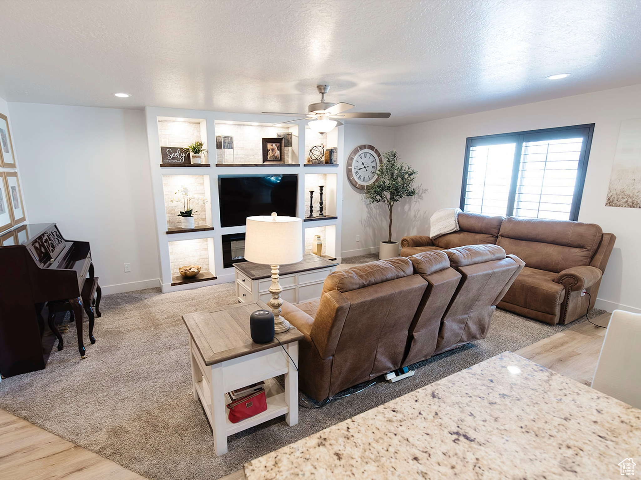 Living area featuring baseboards, a ceiling fan, a textured ceiling, and wood finished floors