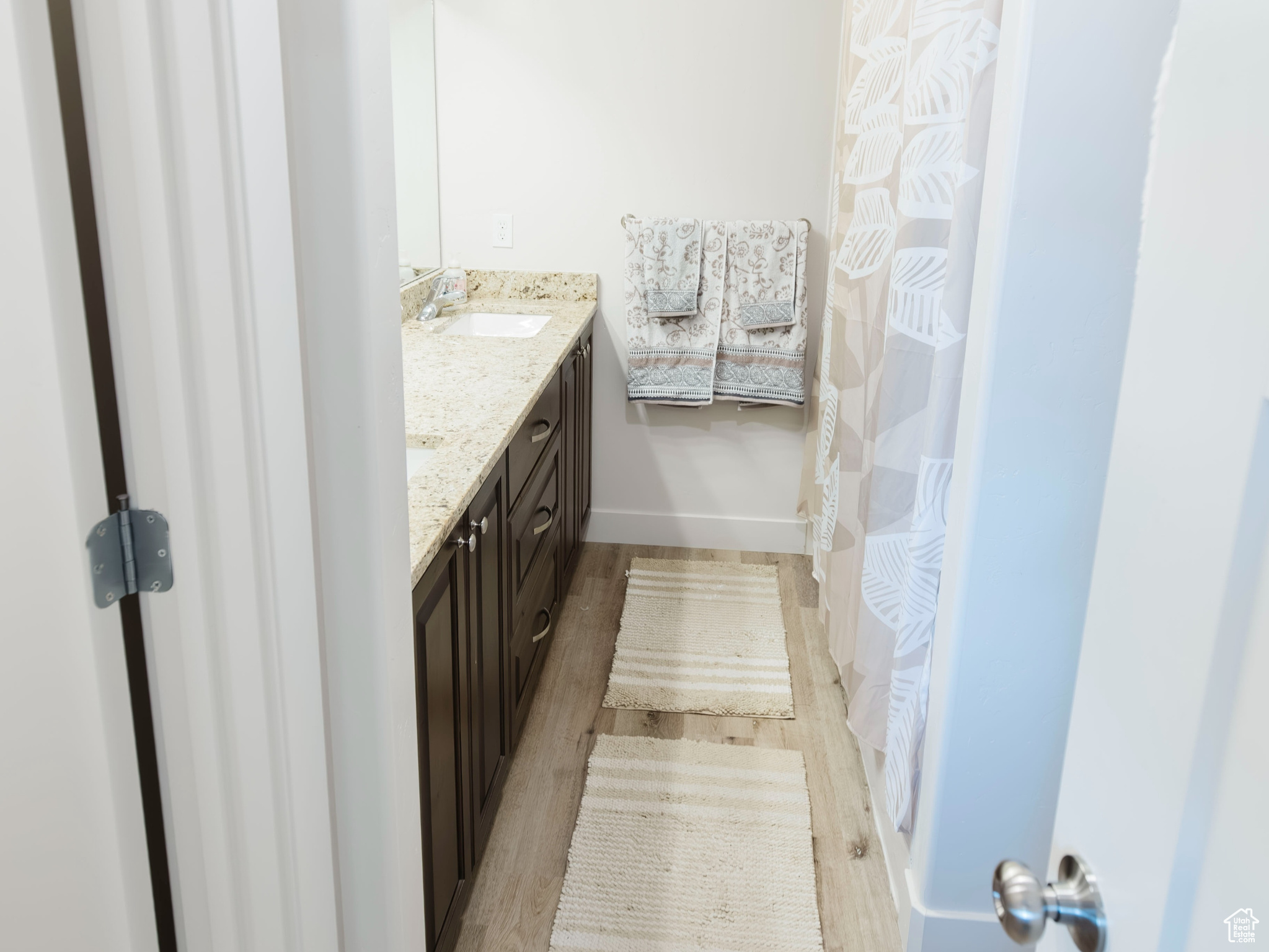 Full bathroom with baseboards, visible vents, wood finished floors, and vanity