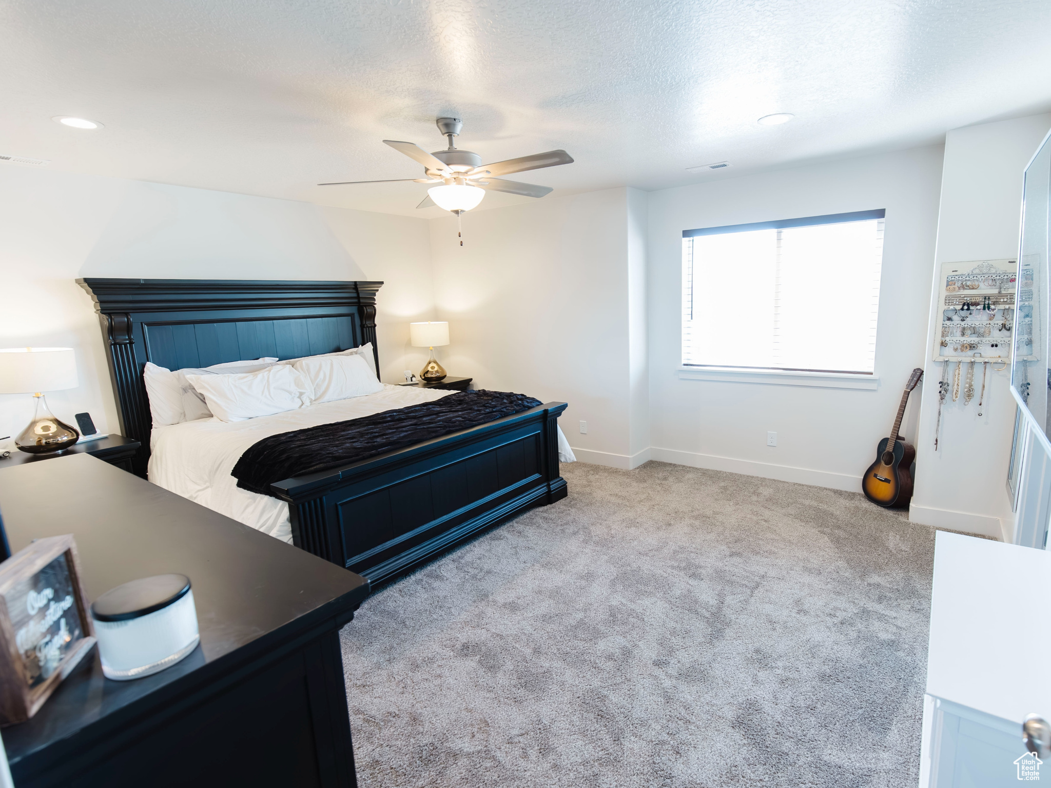 Carpeted bedroom with ceiling fan, a textured ceiling, and baseboards