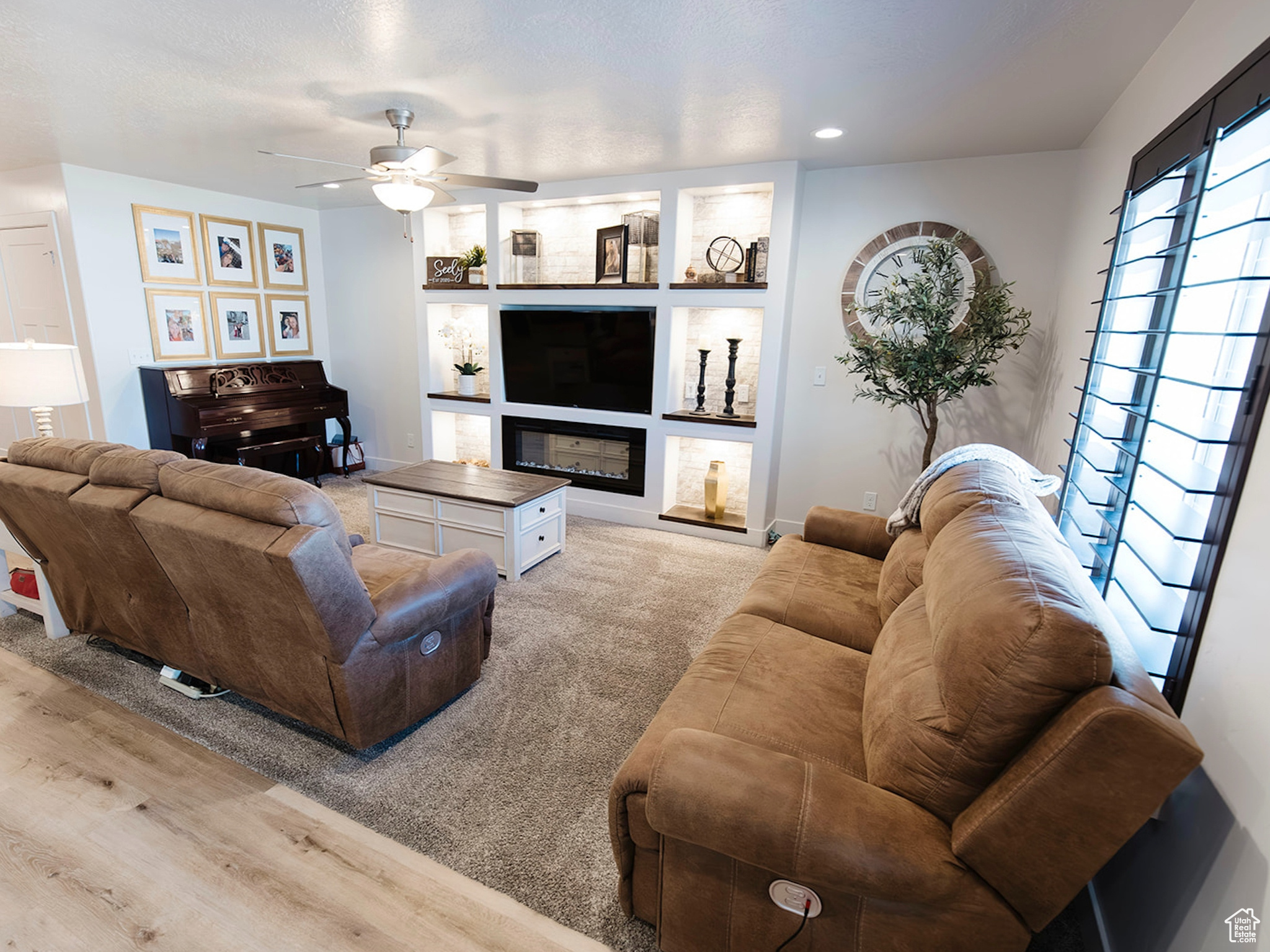 Living room featuring recessed lighting, baseboards, light wood-style floors, built in features, and a glass covered fireplace