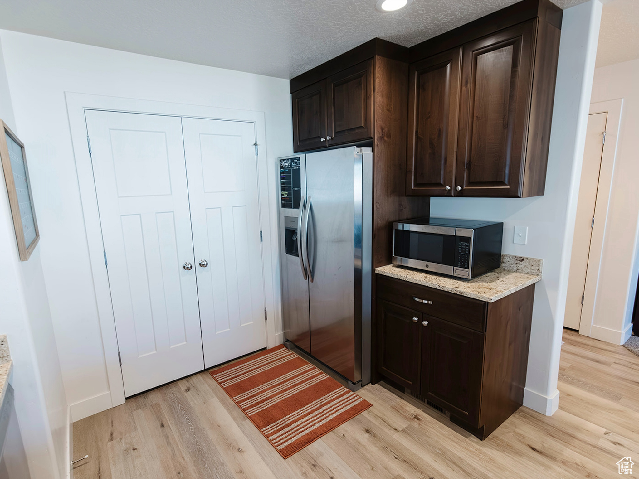 Kitchen featuring stainless steel appliances, light wood-style floors, and dark brown cabinets