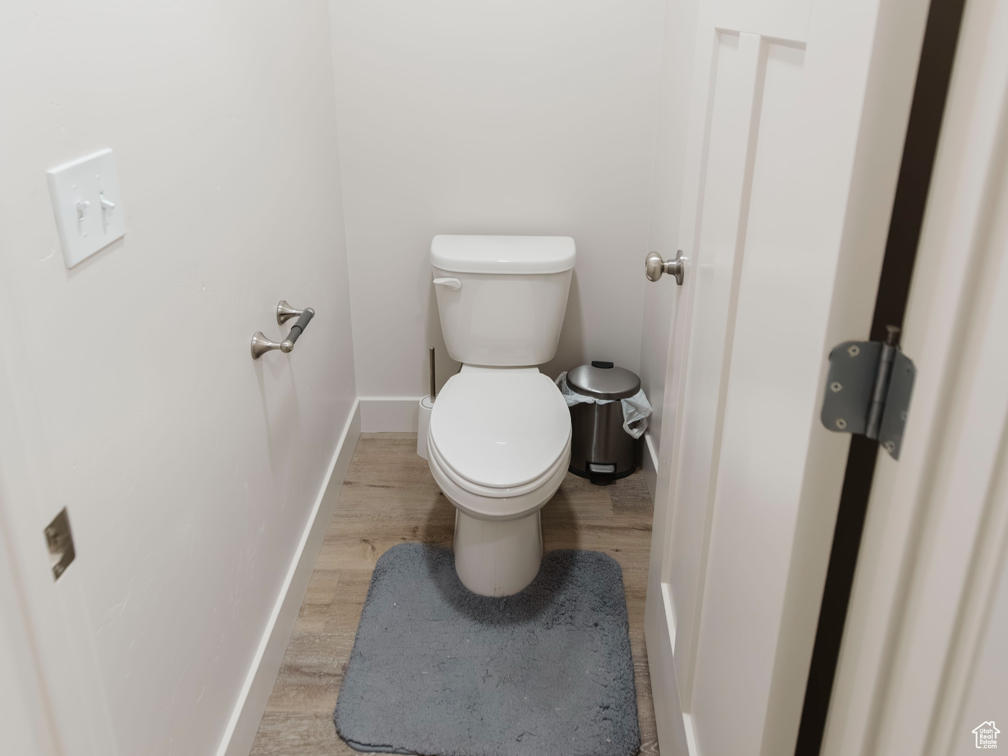 Bathroom featuring toilet, baseboards, and wood finished floors