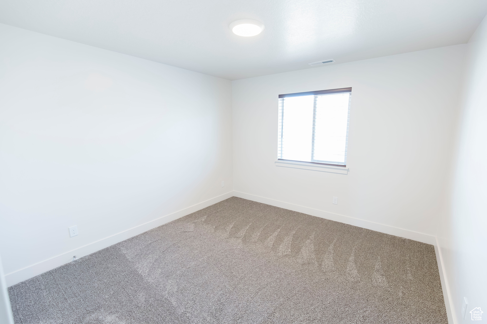 Carpeted spare room with baseboards and visible vents