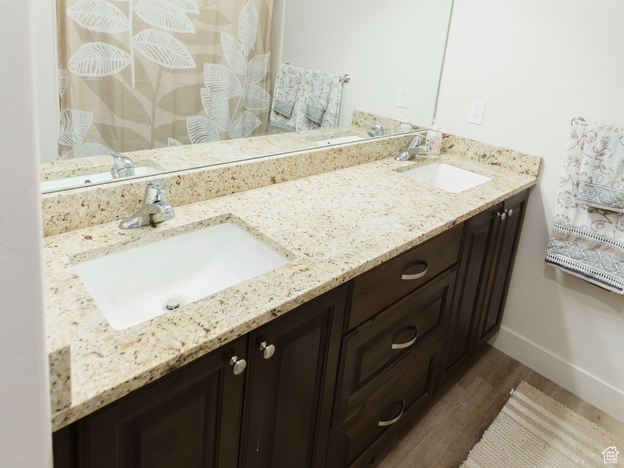 Bathroom featuring double vanity, a sink, and wood finished floors