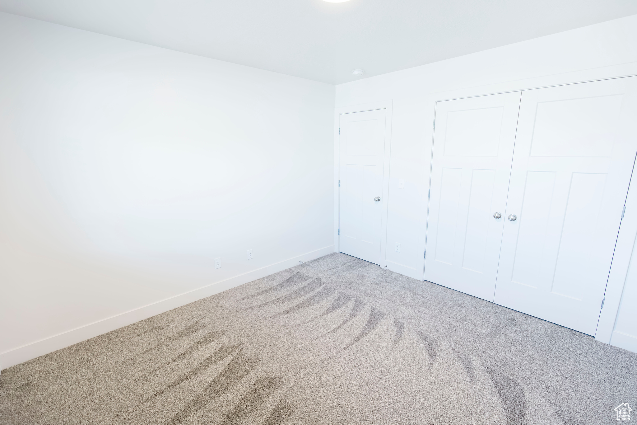 Unfurnished bedroom with carpet, a closet, and baseboards