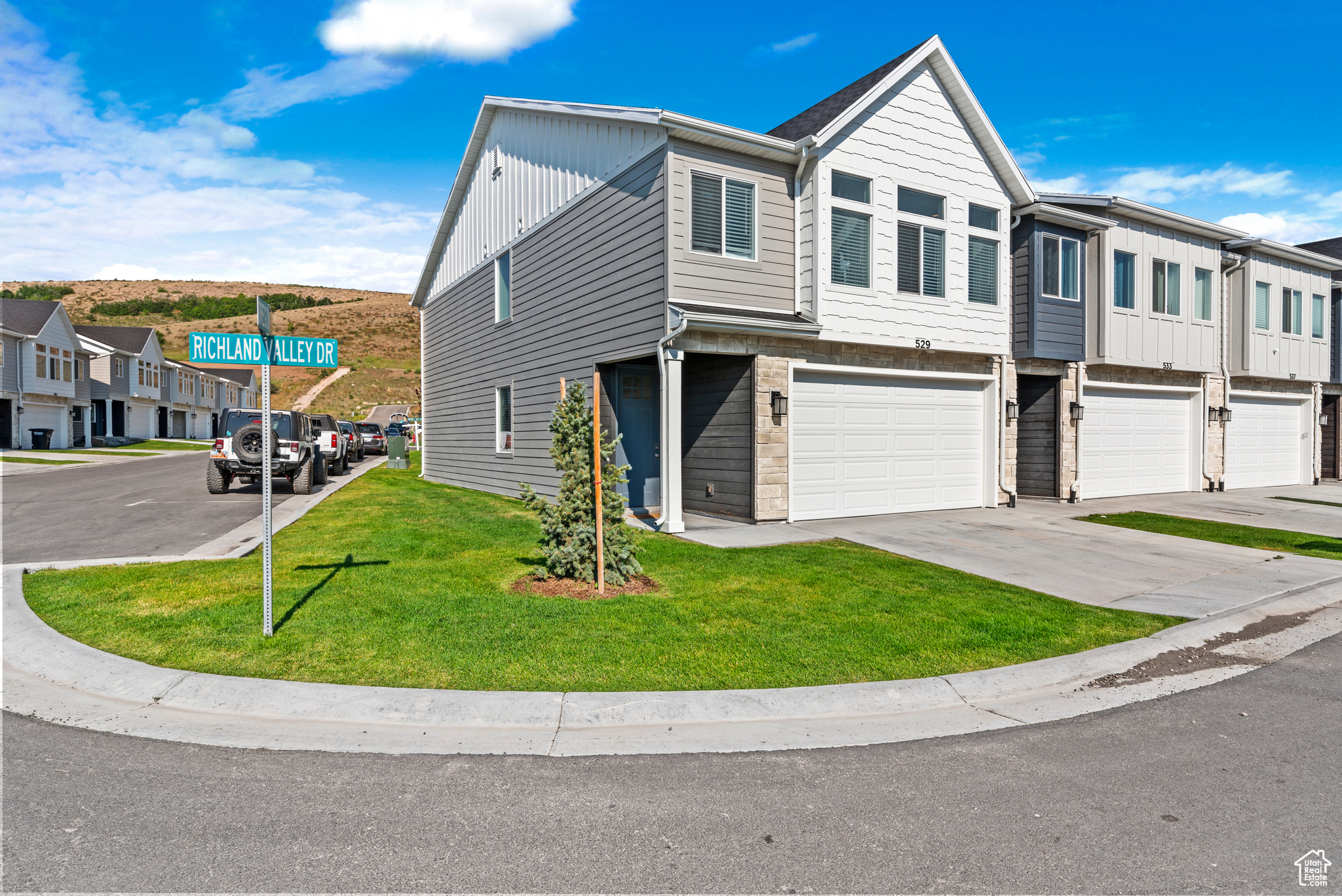 Multi unit property with driveway, a residential view, board and batten siding, a front yard, and a garage