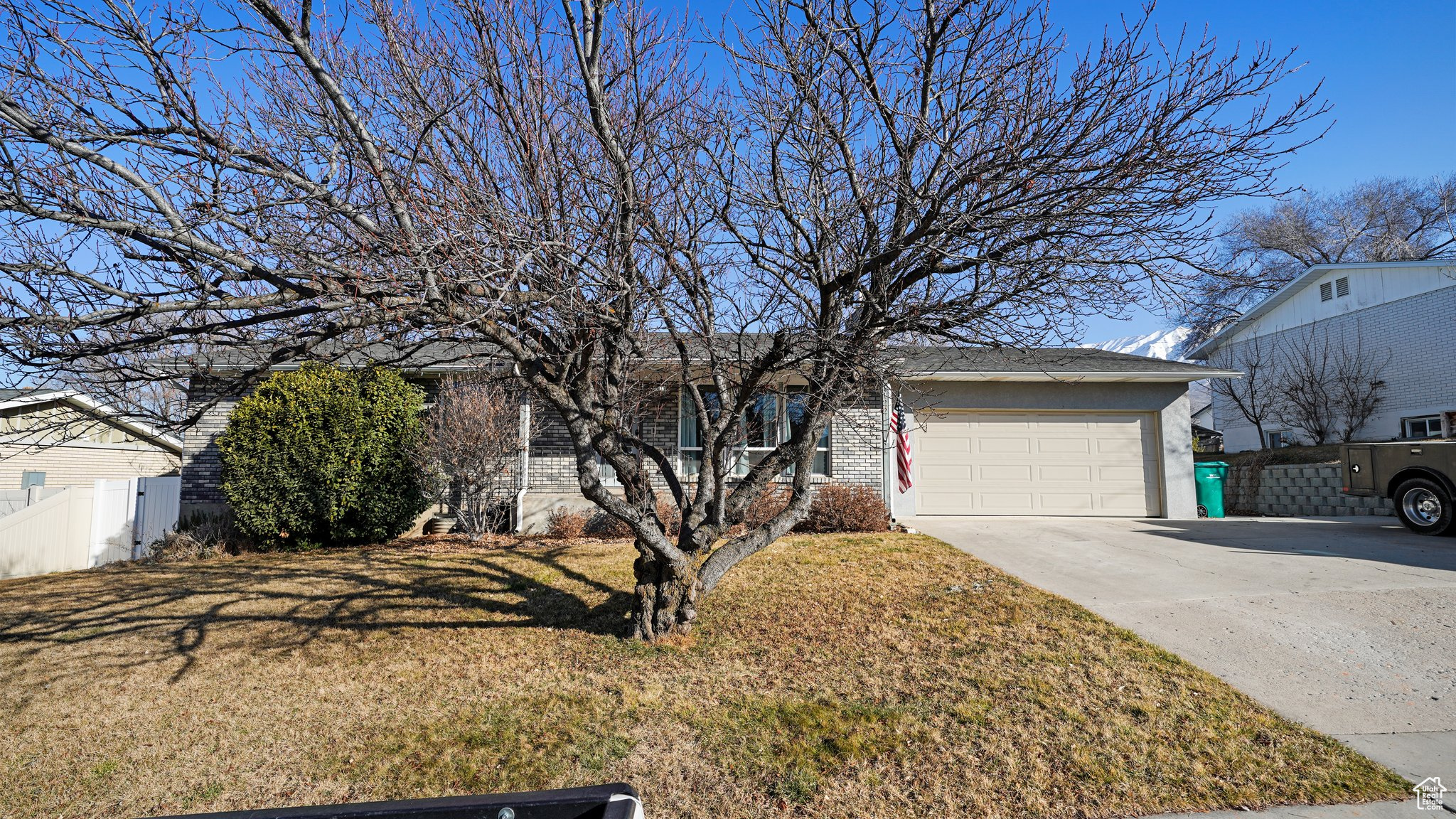 View of front of property featuring a front yard, fence, an attached garage, stucco siding, and concrete driveway