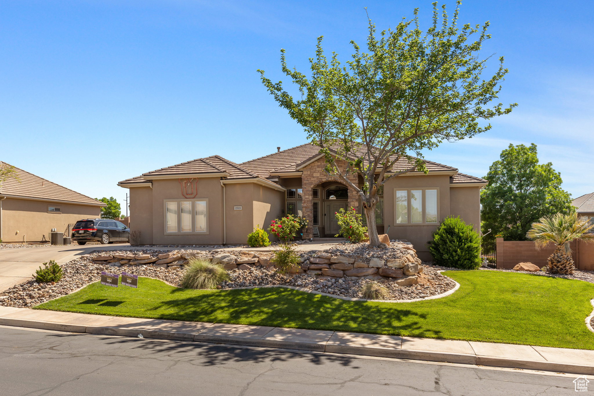 Mediterranean / spanish-style home with a front lawn, concrete driveway, stone siding, and stucco siding