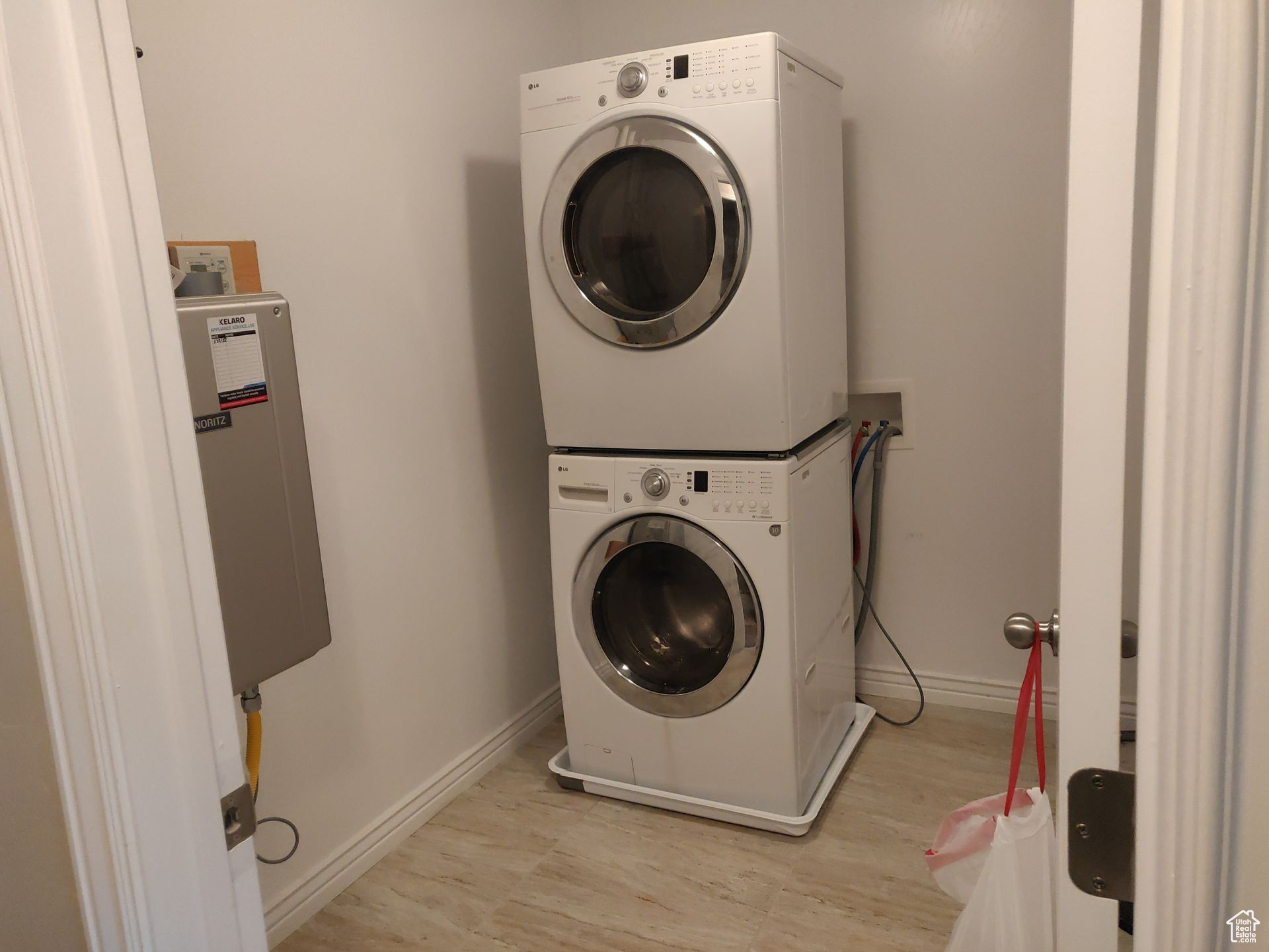 Clothes washing area with laundry area, baseboards, and stacked washer / drying machine