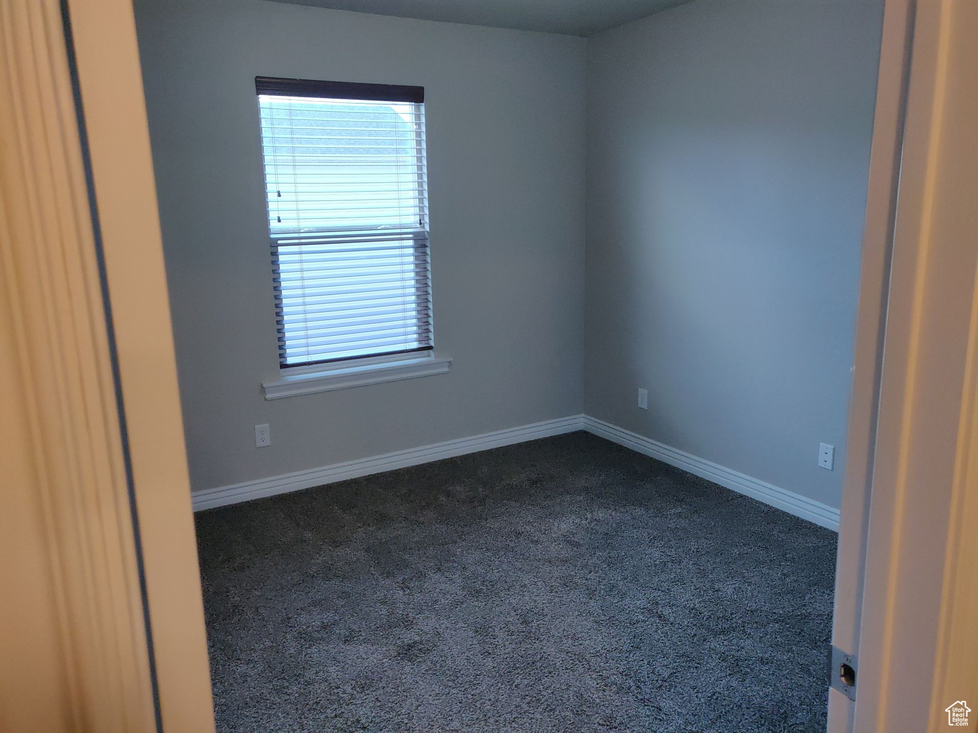 Spare room featuring baseboards and dark carpet