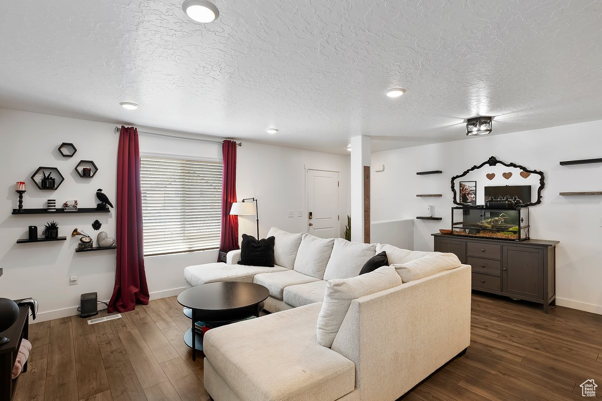 Living room with baseboards, a textured ceiling, and dark wood finished floors