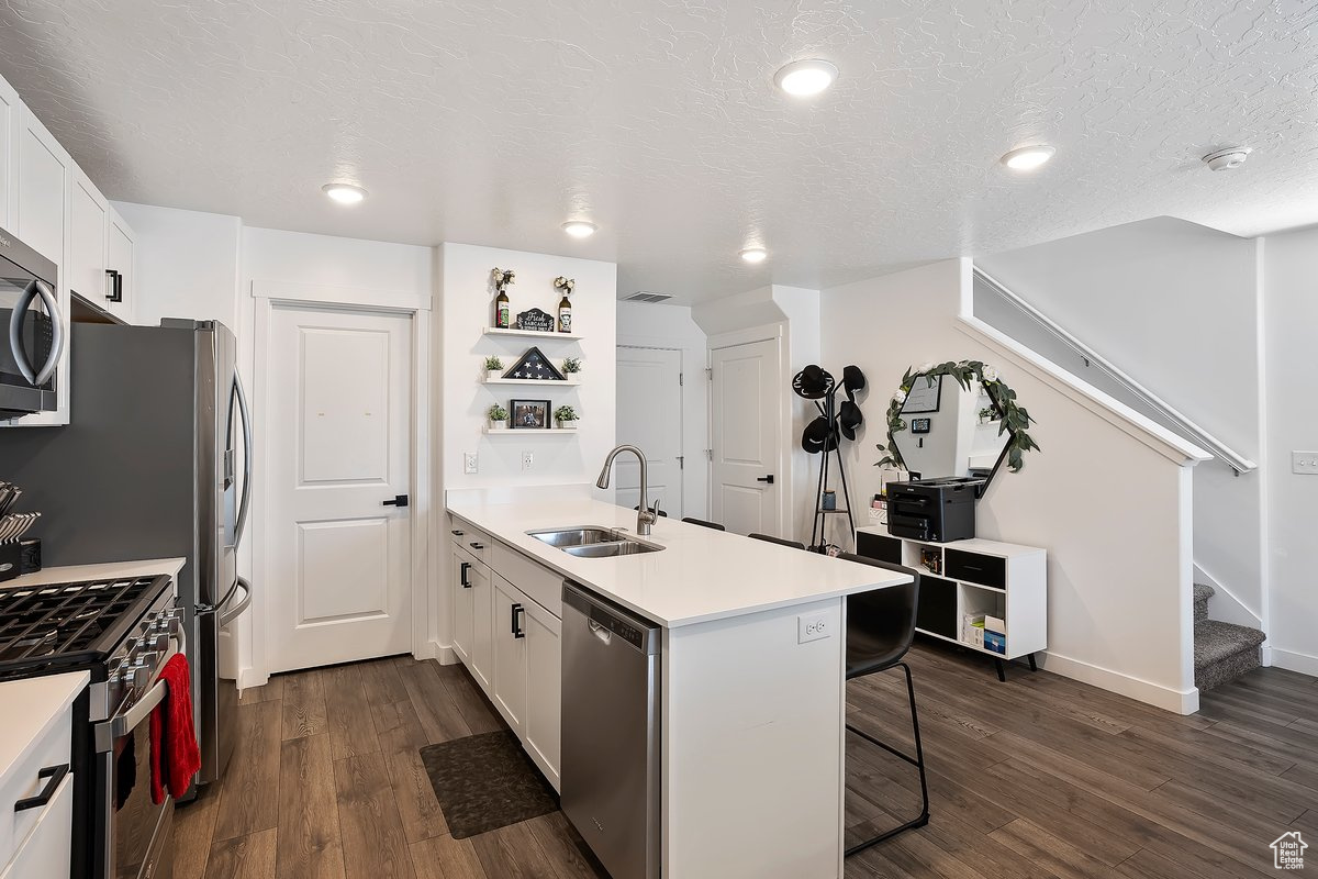 Kitchen with a breakfast bar area, a peninsula, stainless steel appliances, a sink, and white cabinets