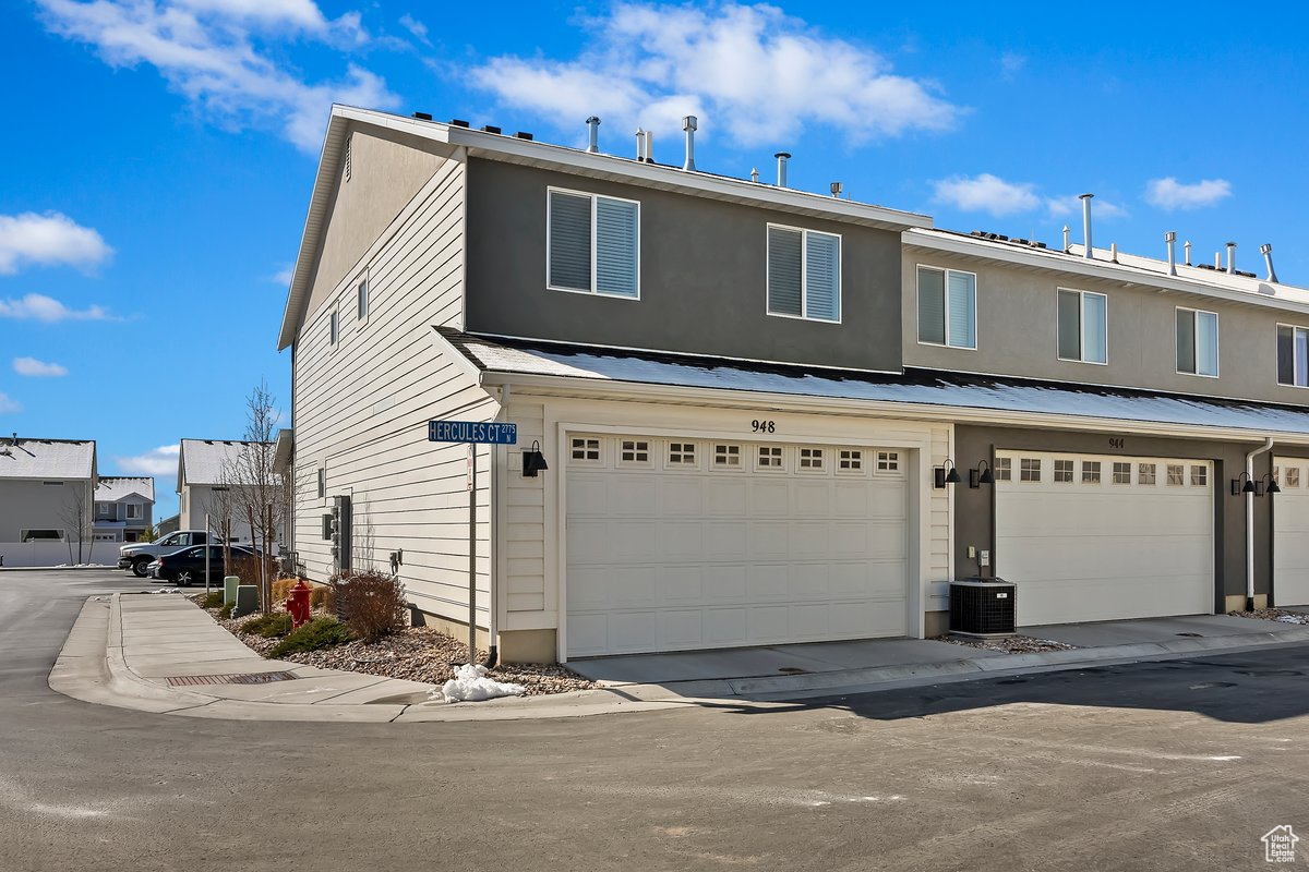 View of property with central AC unit and an attached garage