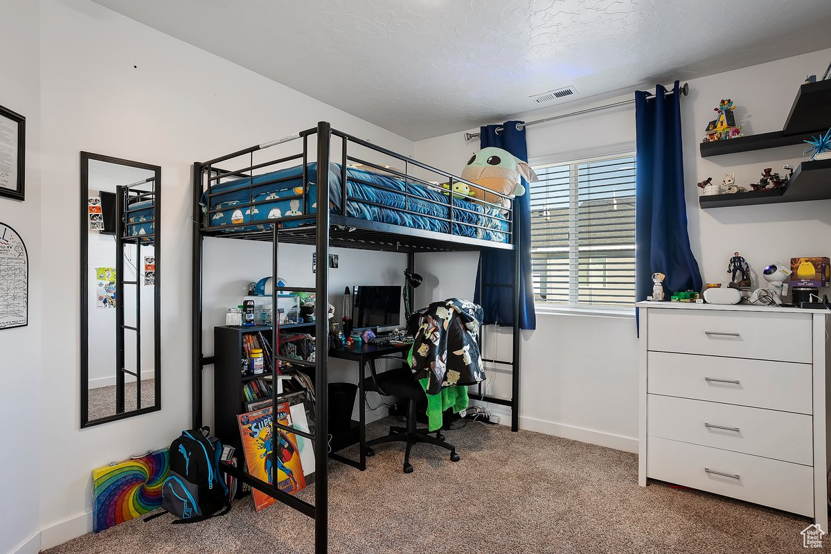 Bedroom featuring visible vents, a textured ceiling, baseboards, and carpet