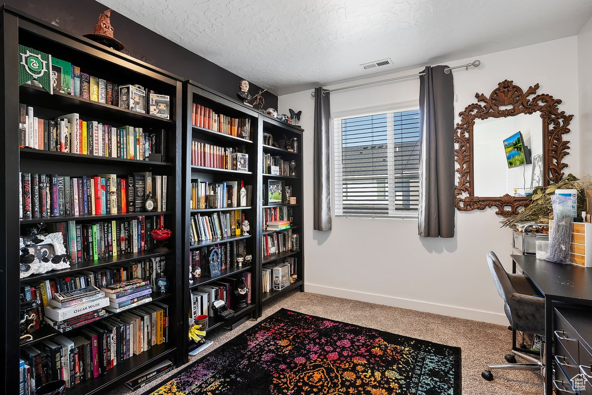 Carpeted home office with visible vents, a textured ceiling, and baseboards