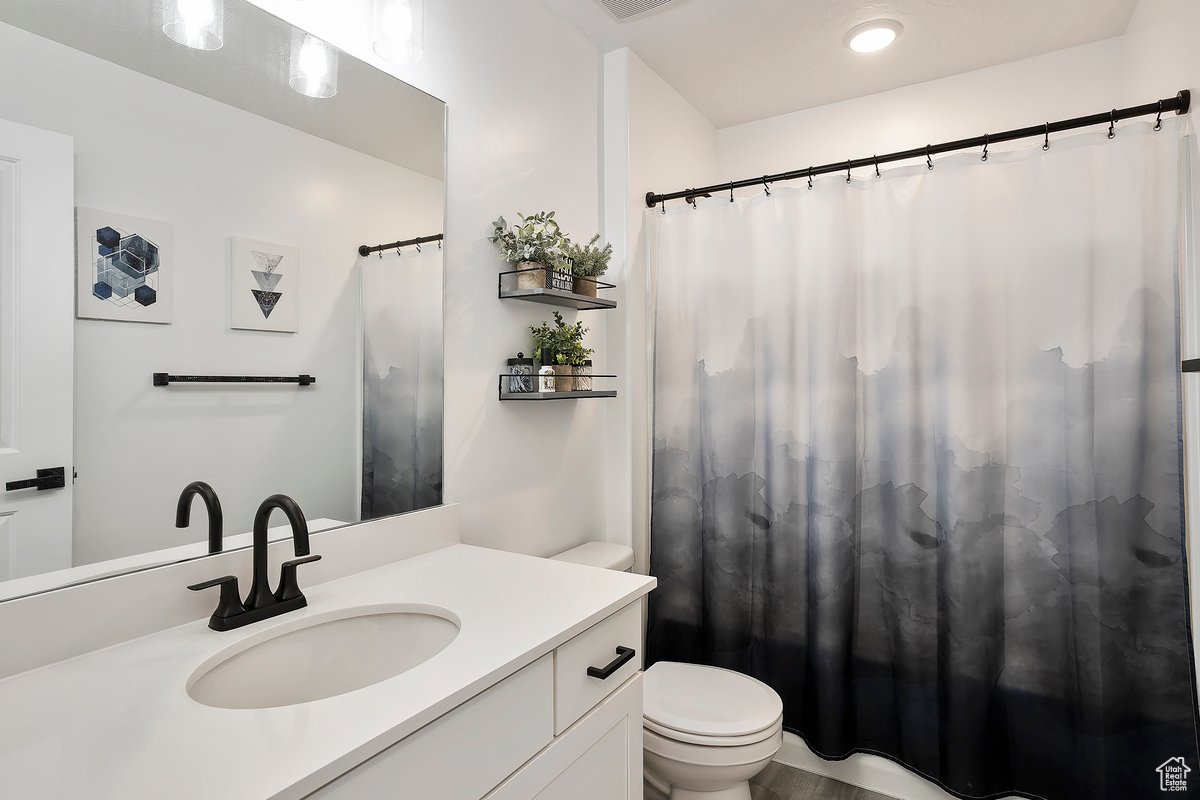 Full bath featuring curtained shower, toilet, visible vents, and vanity