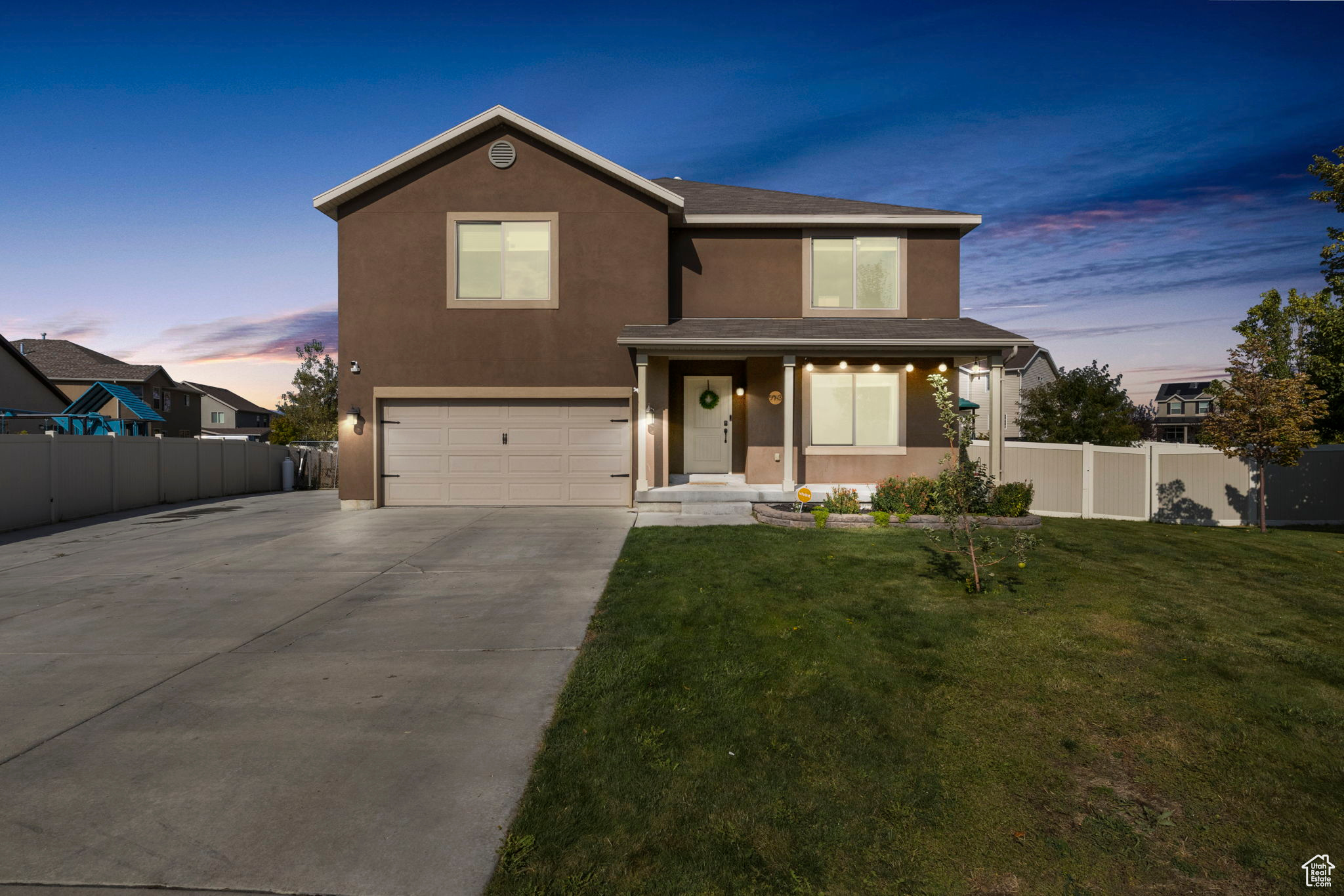 Traditional-style home with fence, stucco siding, a lawn, a garage, and driveway