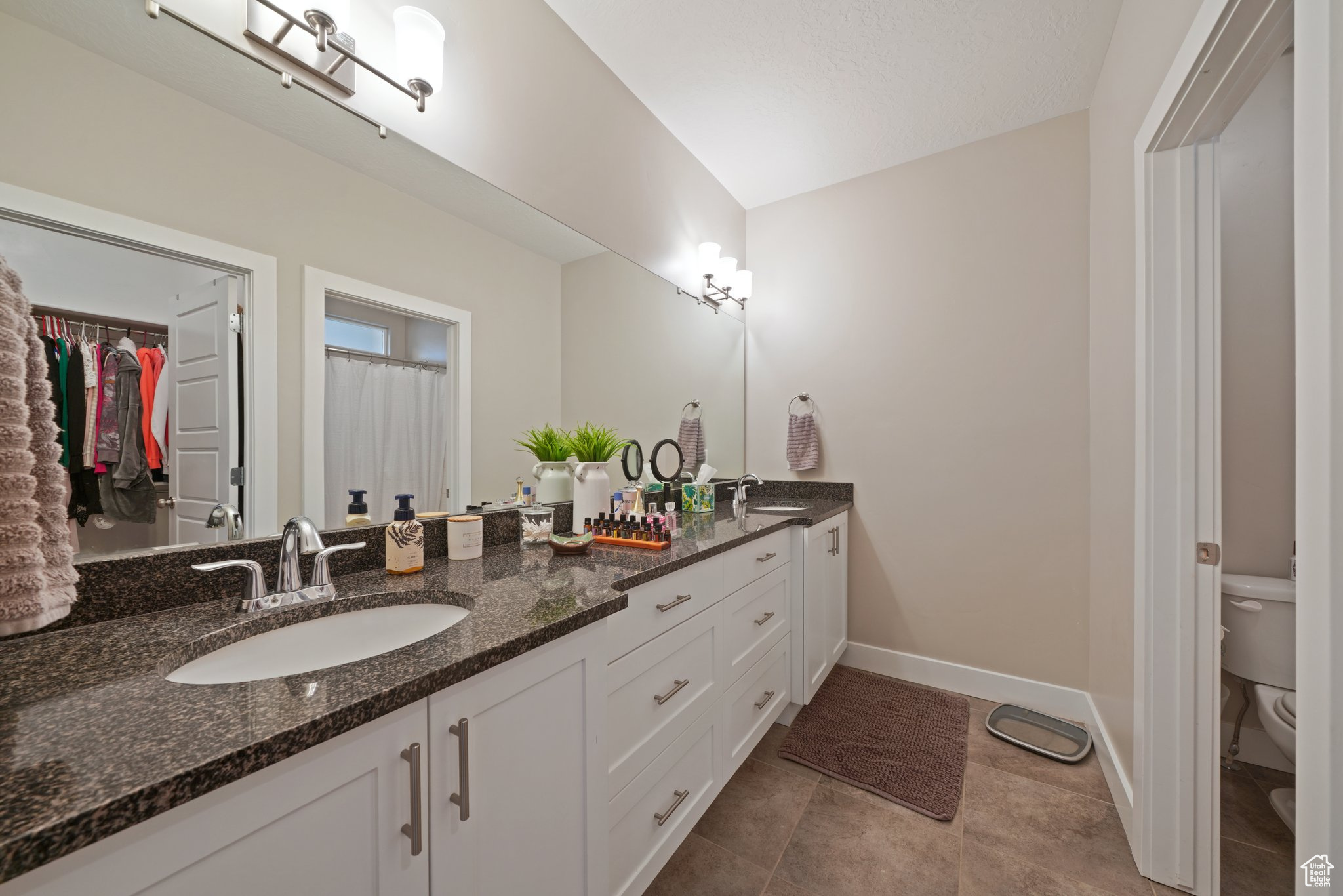 Full bath featuring double vanity, toilet, baseboards, and a sink