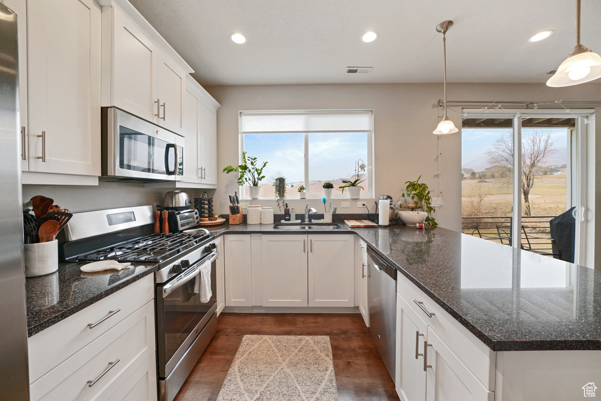 Kitchen with visible vents, a sink, white cabinetry, appliances with stainless steel finishes, and a peninsula