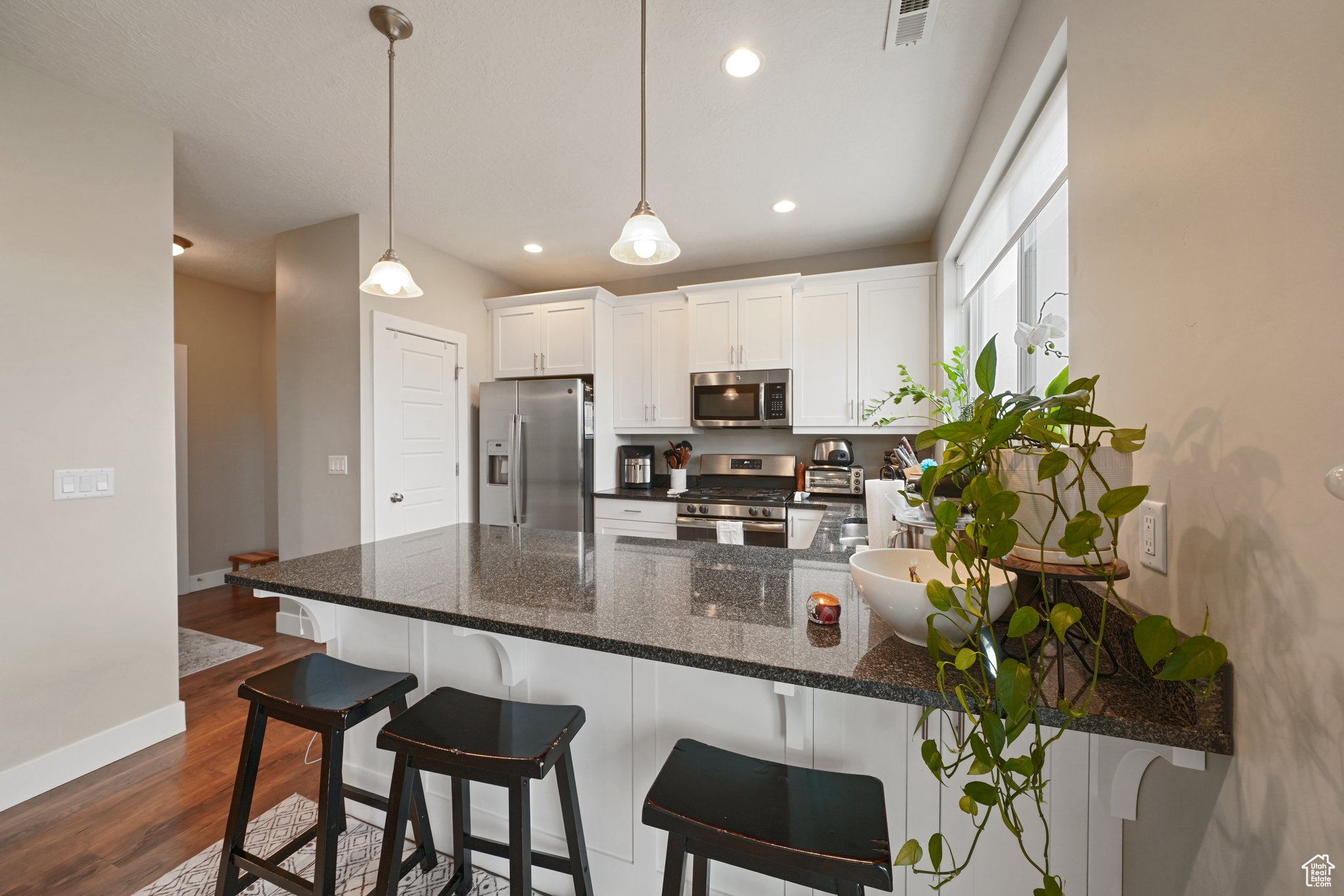 Kitchen with visible vents, appliances with stainless steel finishes, a peninsula, dark wood-style floors, and white cabinets