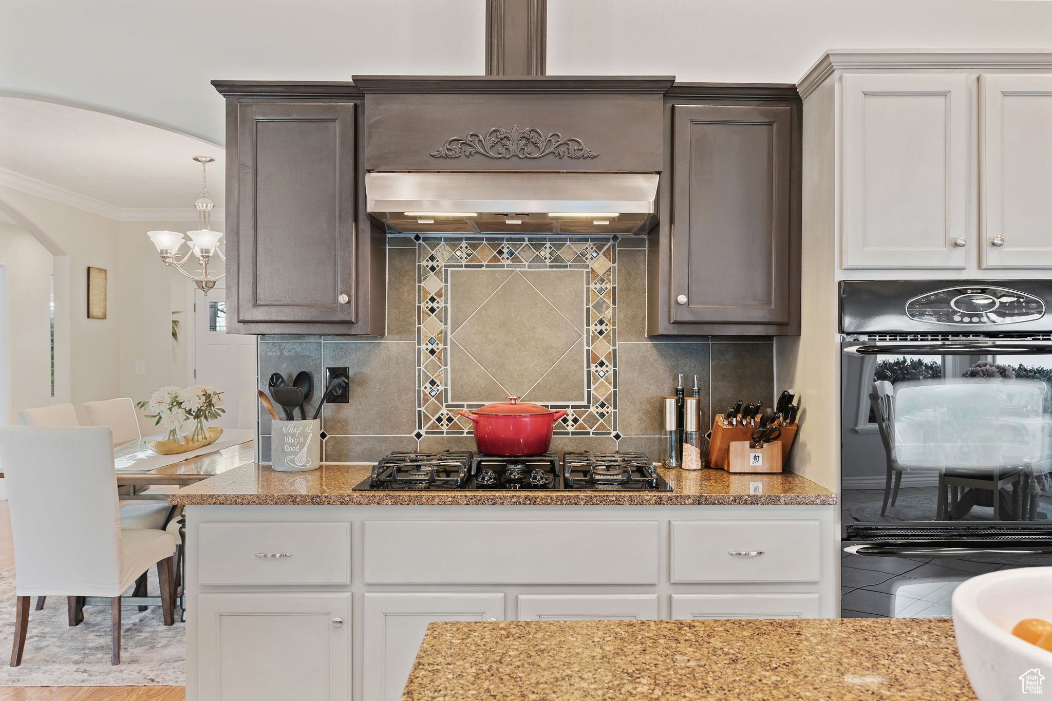 Double ovens. Gas stove and range hood. Ornate backsplash.